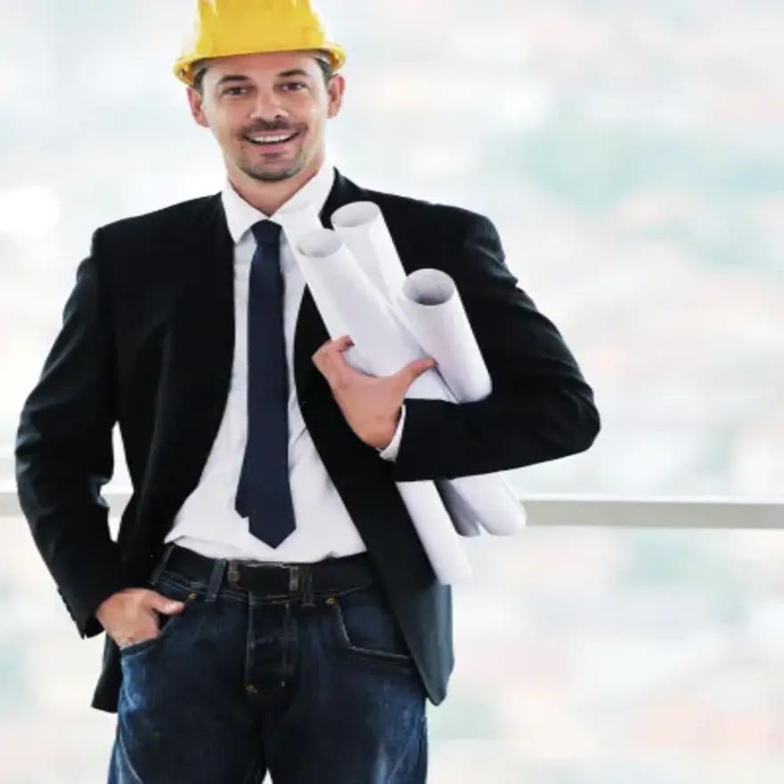 Un homme en costume et casque de chantier tenant des plans de construction