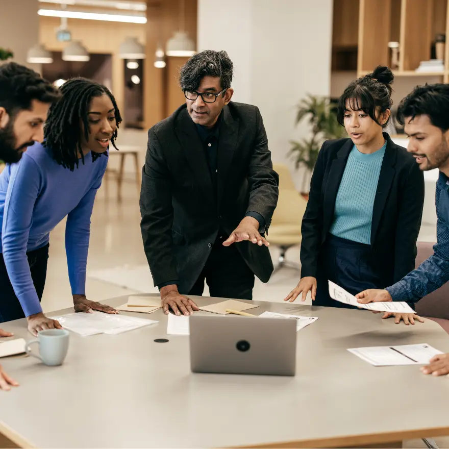 Un groupe de personnes se rassemble autour d'une table avec un ordinateur portable ouvert