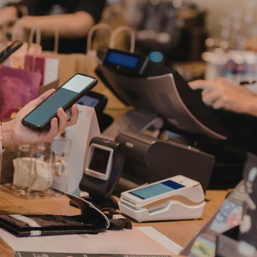 Une personne utilise un smartphone à un comptoir de caisse.