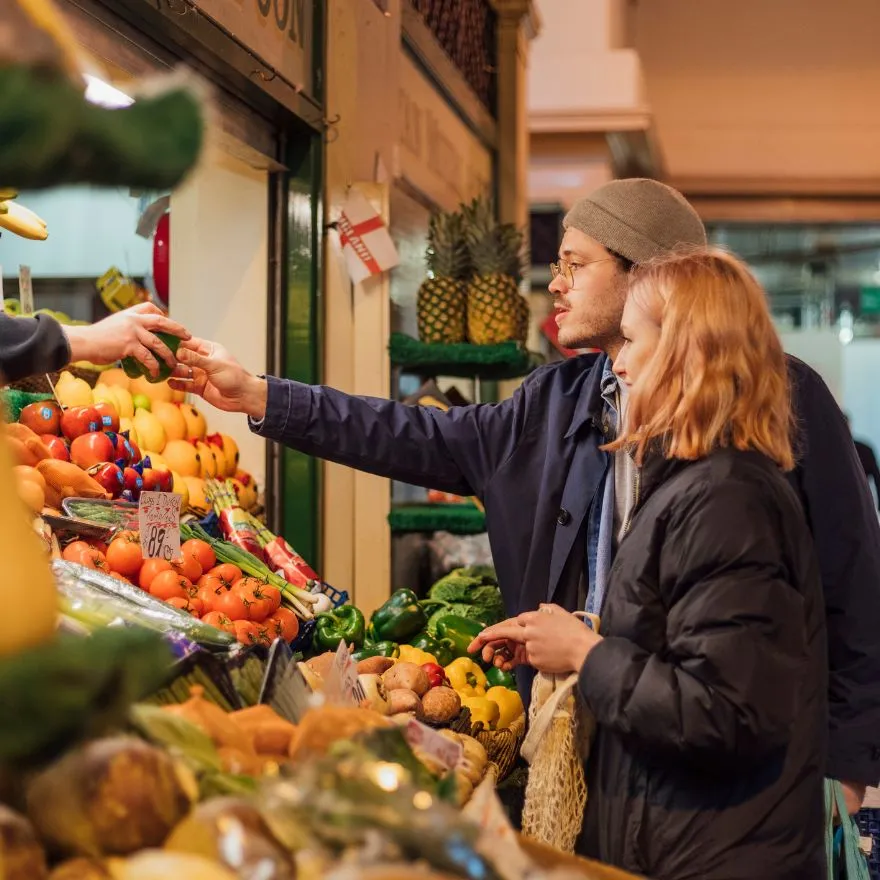 Un homme et une femme examinent des produits frais dans un marché animé