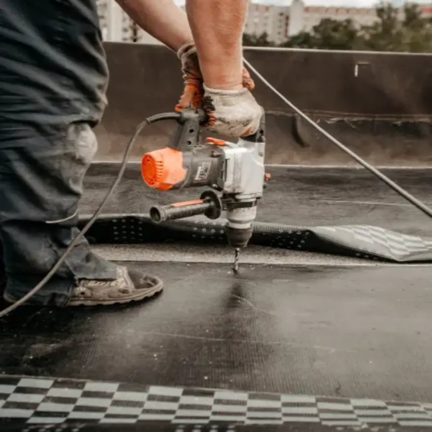 Un homme utilise une perceuse pour installer un toit, concentré sur son travail
