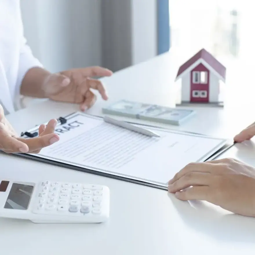 Deux personnes assises à une table, utilisant une calculatrice et examinant des documents.