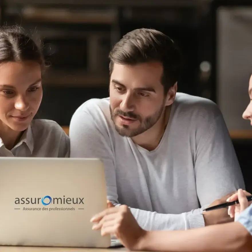 Trois personnes devant un ordinateur du groupe Assuromieux.