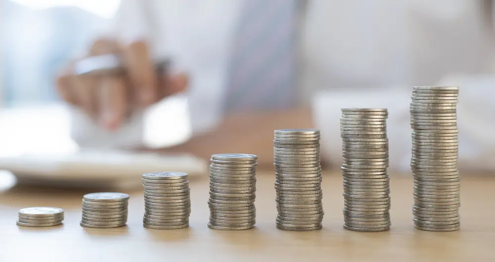 Un homme en costume empile des pièces de monnaie sur une table