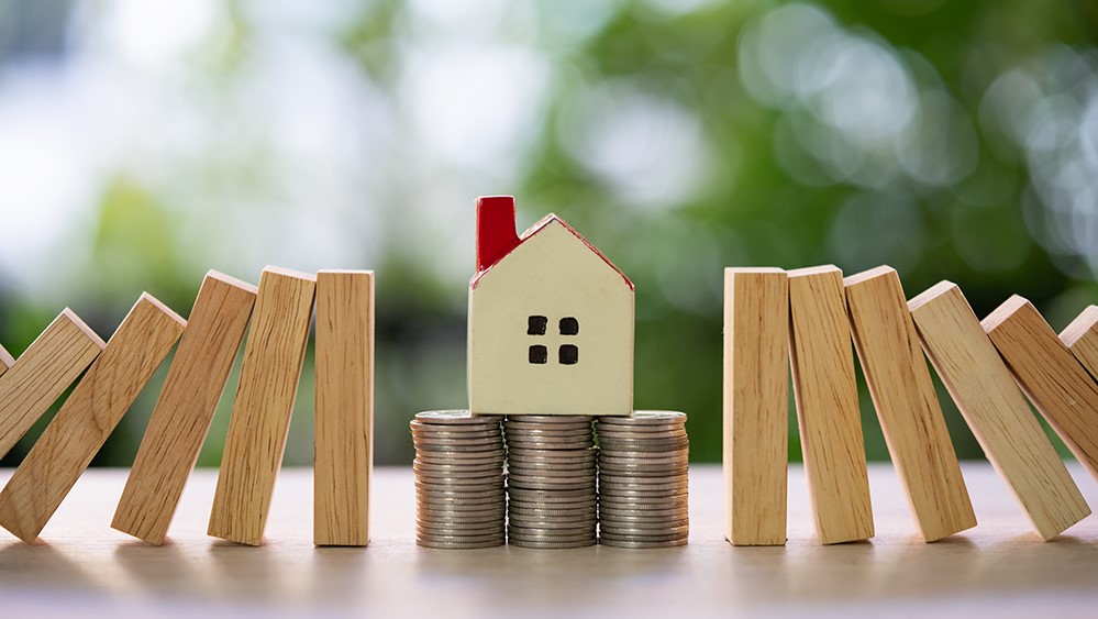 Une pile de pièces de monnaie avec une maison placée au centre, symbolisant l'épargne et l'investissement immobilier