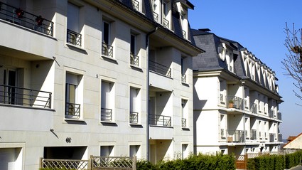 Une rangée de bâtiments d'appartements le long d'une rue, avec des fenêtres et balcons visibles