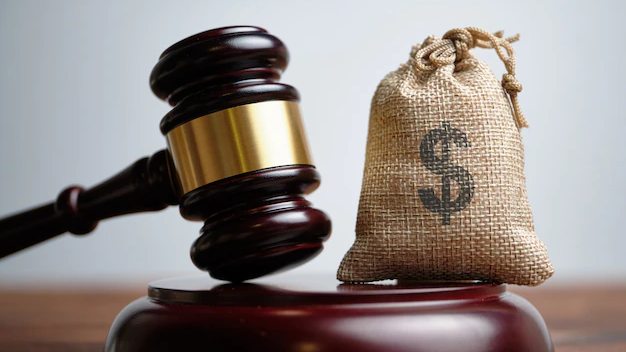 Un marteau de juge posé à côté d'un sac d'argent, symbolisant la justice et les enjeux financiers