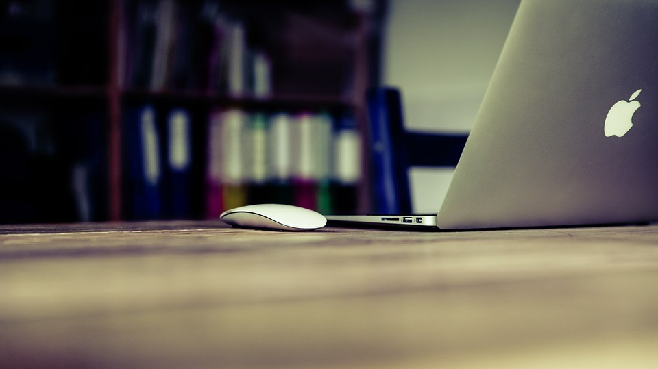 Un ordinateur portable posé sur un bureau en bois, avec un fond neutre