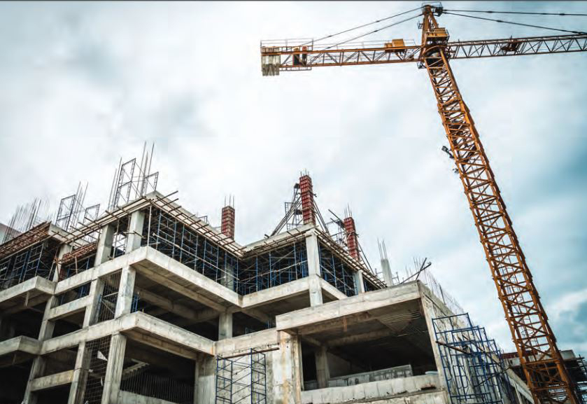 Grue de construction sur un bâtiment en cours de construction, avec des matériaux et des ouvriers visibles autour