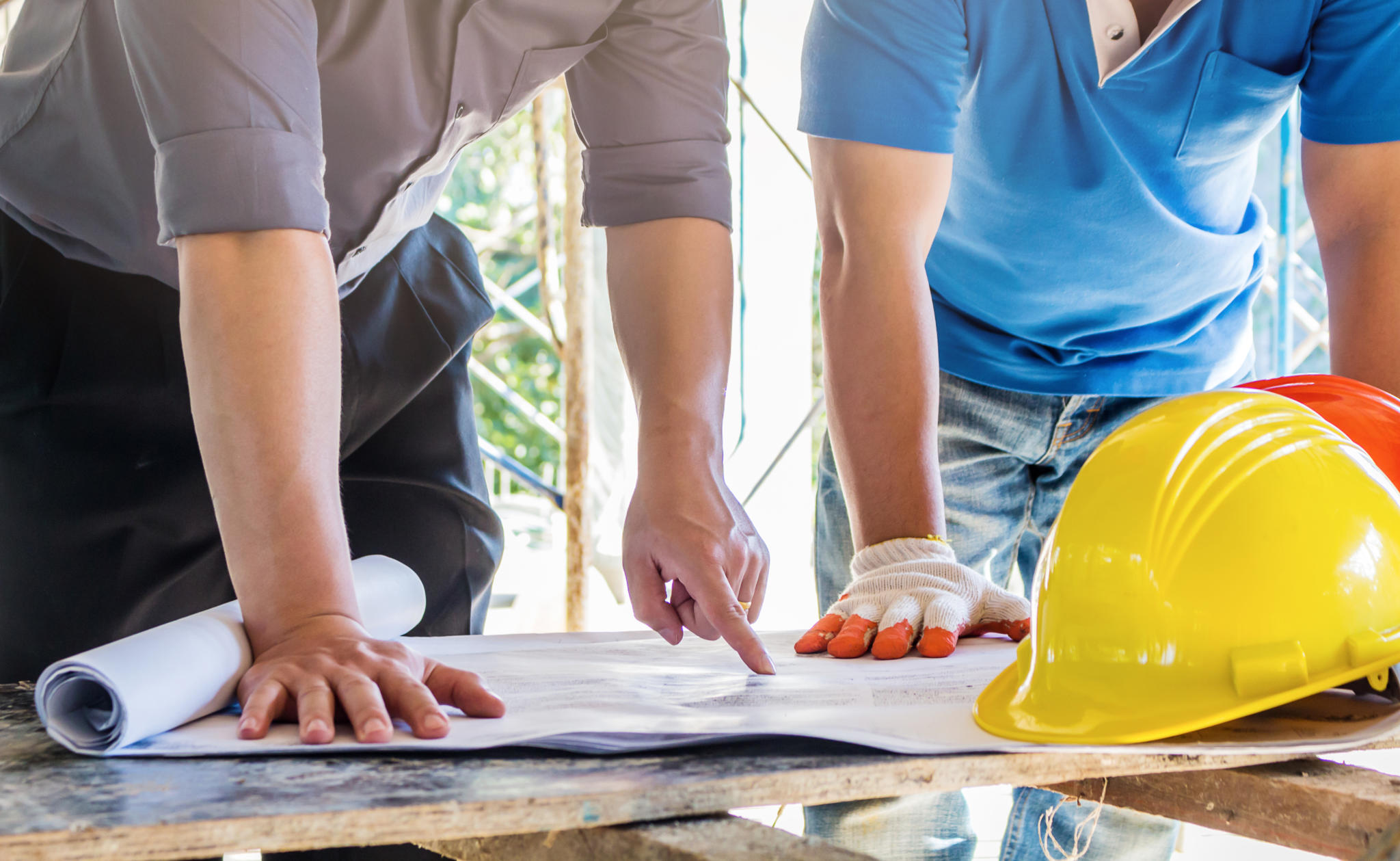 Deux personnes collaborent sur un projet de construction, utilisant des outils et examinant des plans sur un chantier