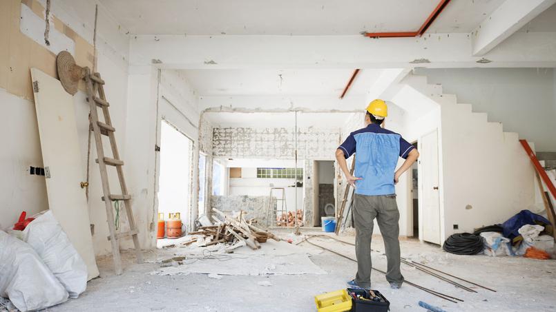 Un homme se tenant dans une pièce remplie d'équipements de construction, avec des outils et des matériaux autour de lui