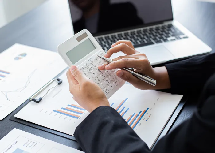 Un individu manipule une calculatrice pour réaliser des opérations numériques