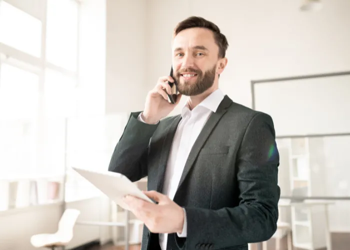 Un homme en costume, utilisant une tablette tout en conversant au téléphone, symbolisant une interaction professionnelle