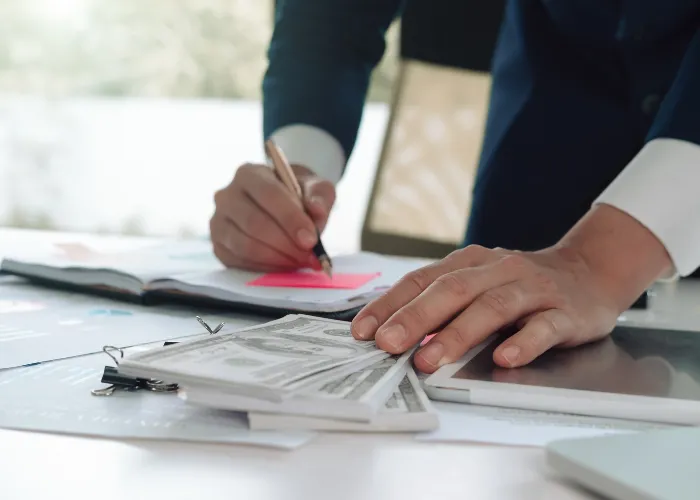 Une personne en costume écrit sur une feuille de papier, concentrée sur sa tâche