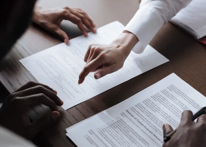 Trois personnes assises à une table, entourées de papiers et de stylos, engagées dans une discussion ou un travail collaboratif