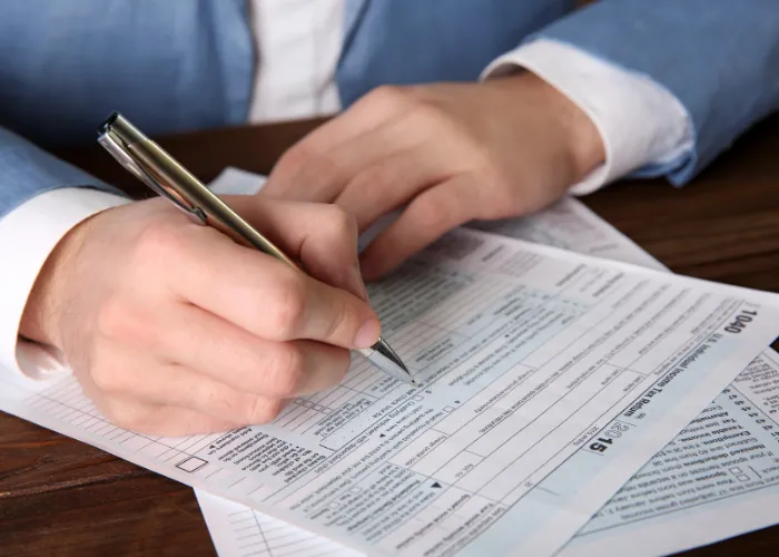 Un homme en costume travaille sur un formulaire fiscal, stylo à la main