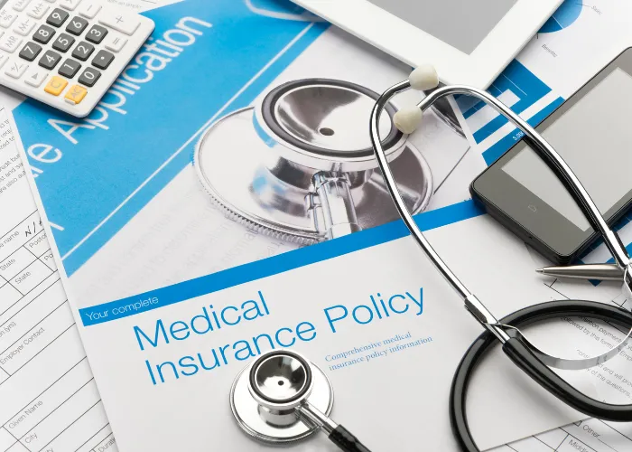 Assurance médicale sur un bureau, avec un stéthoscope et une calculatrice, symbolisant la gestion des soins de santé